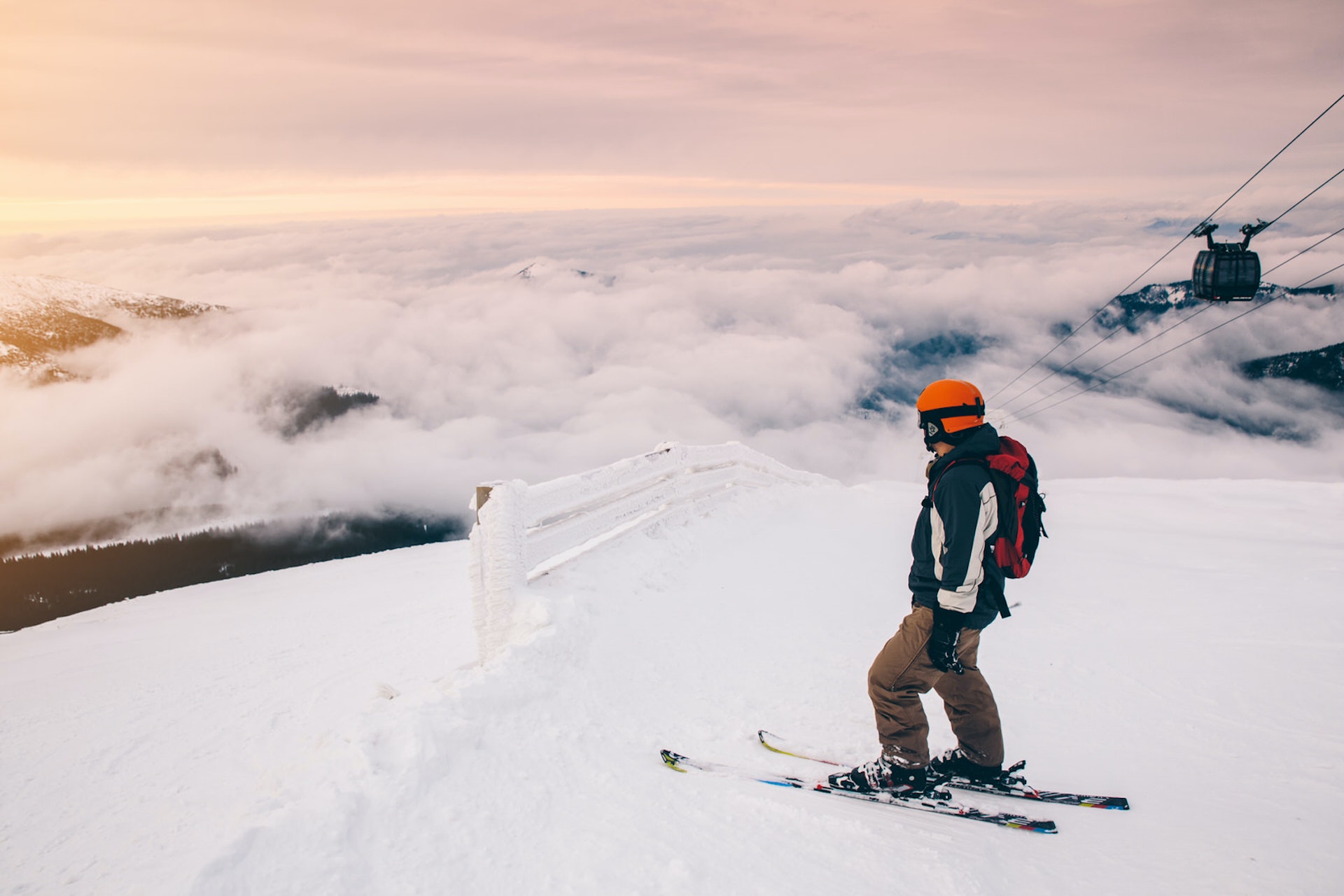 Лыжник на вершине горы в Словакии;  Внизу облачность, а справа поднимается кресельный подъемник.